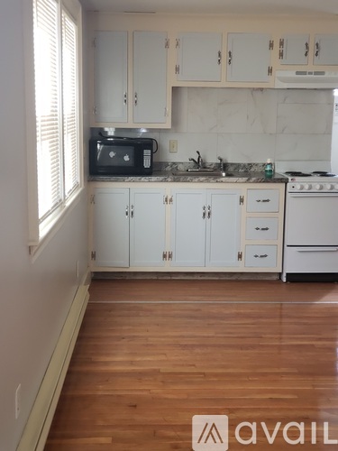 A kitchen with white cabinets and a wooden floor.