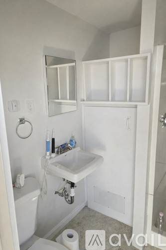 A white bathroom with a toilet, sink, and mirror.