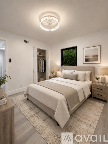 A bedroom with a large bed, a window with a view of trees, and a framed picture on the wall.
