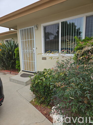 A house with a white gate and a car parked in front.