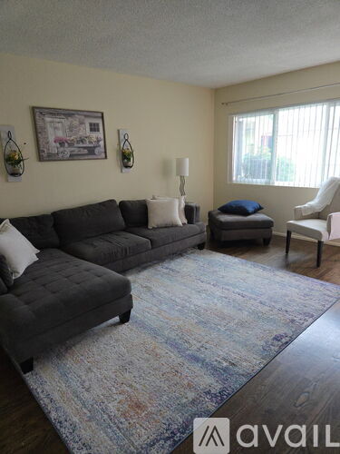 A living room with a grey couch, a white chair, and a blue rug.