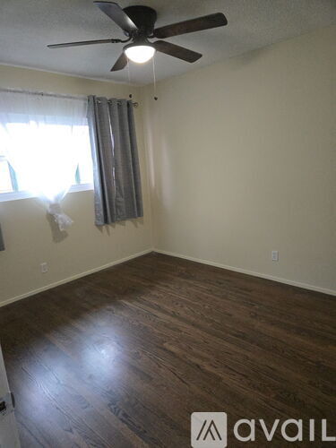 A room with a ceiling fan and wooden flooring.