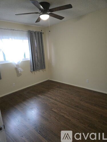 A room with a ceiling fan and wooden flooring.