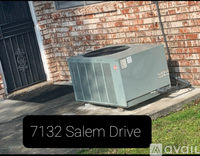 An air conditioner unit is placed on the ground outside a building.