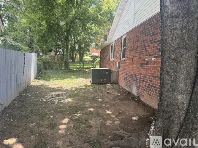 A backyard with a tree, a fence, and a brick building.