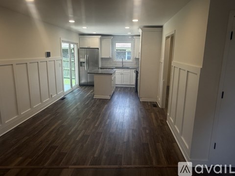 A kitchen with dark wood floors and white walls.
