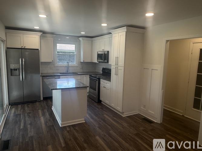 A kitchen with wooden floors and white cabinets.