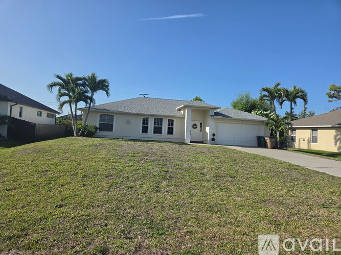 A house with a lawn and palm trees in front.