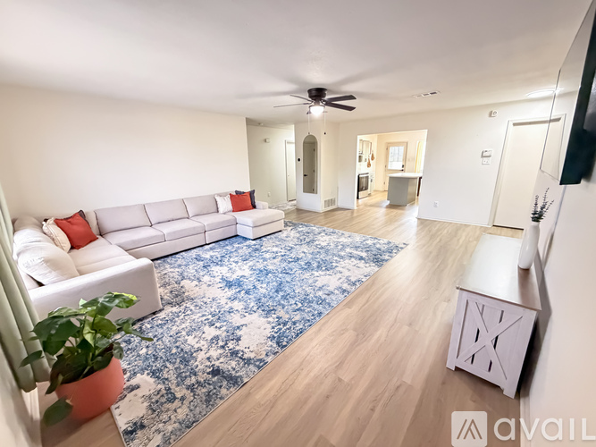 A living room with a white couch and a blue patterned rug.