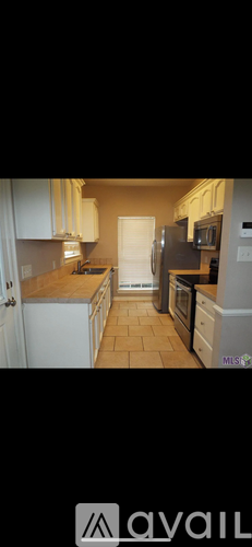 A kitchen with white cabinets and a tiled floor.