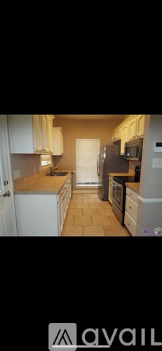 A kitchen with white cabinets and a tiled floor.