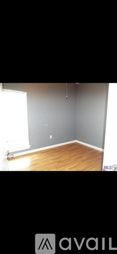 A room with wooden flooring and a grey wall.