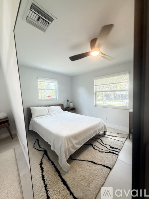 A bedroom with a bed, a ceiling fan, and a rug.