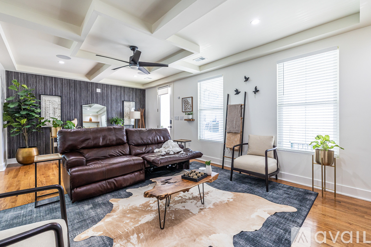 A living room with a brown leather couch and a cowhide rug.