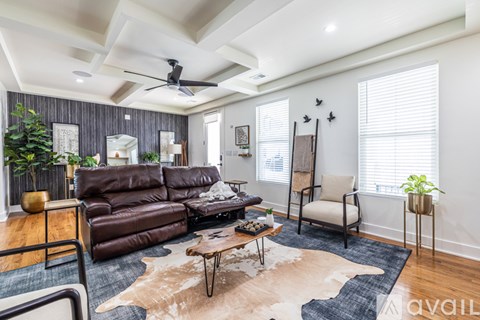A living room with a brown leather couch and a cowhide rug.
