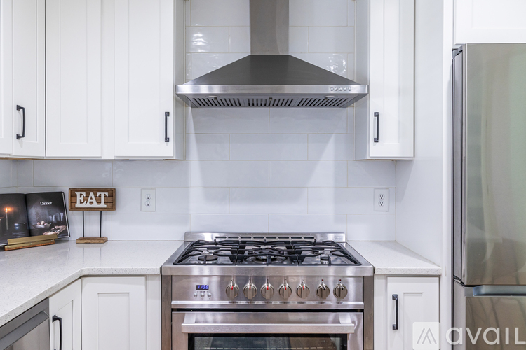 A kitchen with a stove top oven and white cabinets.