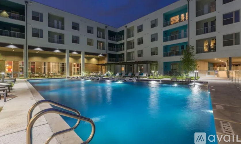 A large swimming pool is surrounded by a building with multiple balconies.