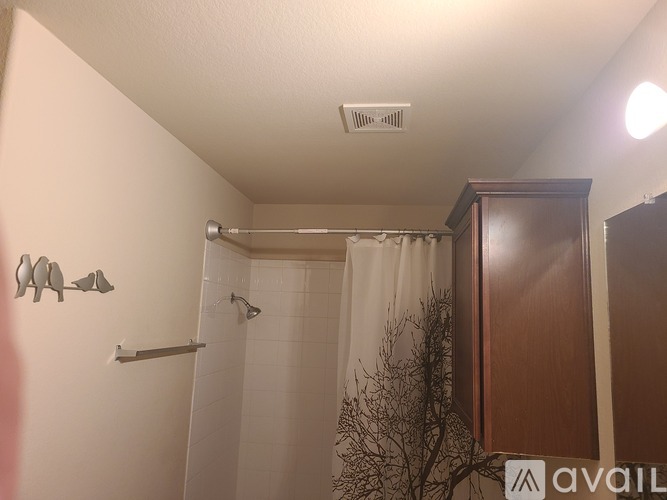 A bathroom with a white shower curtain and a wooden cabinet.