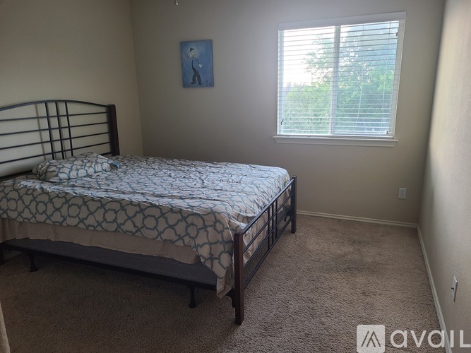 A bedroom with a bed, carpet, and a window with blinds.