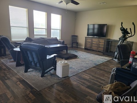 A living room with a black couch and a television on a wooden cabinet.