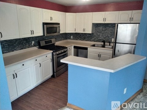 A kitchen with a blue island and white cabinets.