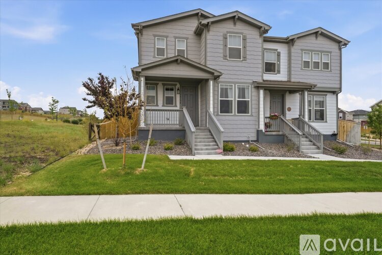 A grey house with a white fence and a green lawn in front.