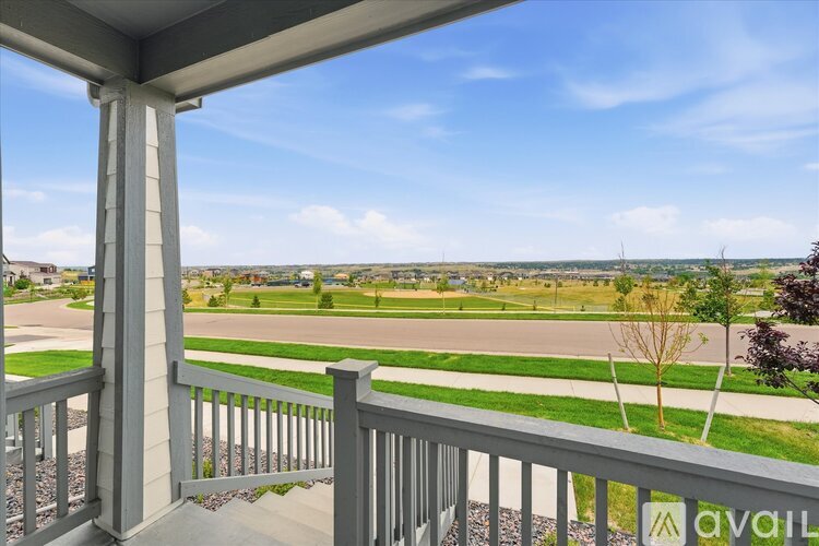 A balcony with a view of a green field and houses.
