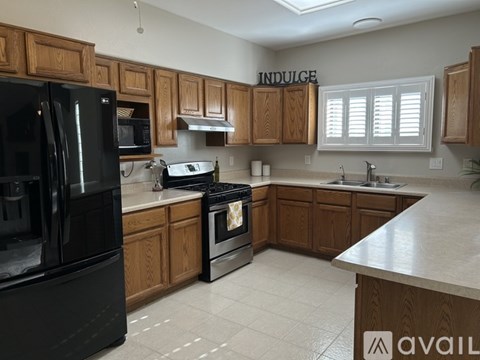 A kitchen with wooden cabinets and a black refrigerator.