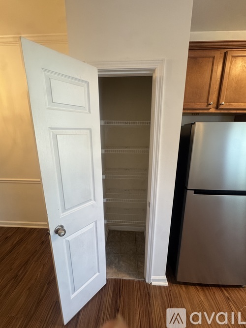 A white door is open to a kitchen with a stainless steel refrigerator.