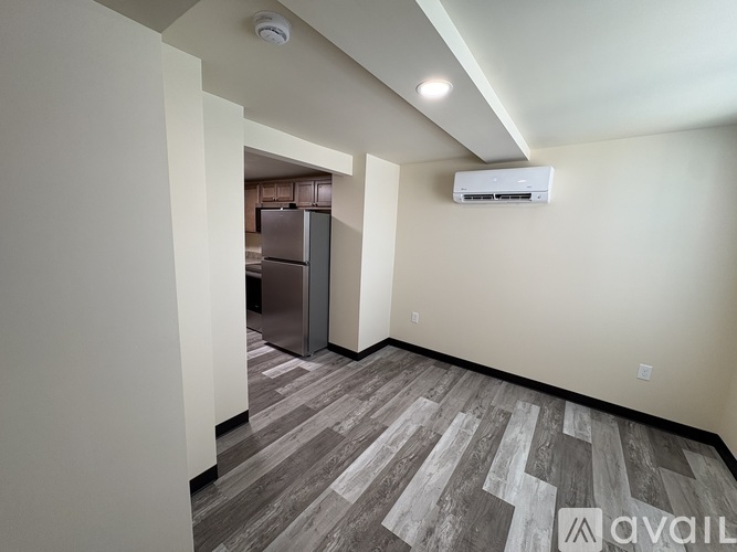 A spacious room with a wooden floor and a wall-mounted air conditioner unit.