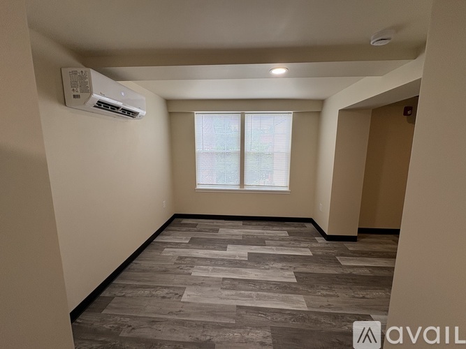 A room with a window and a wall-mounted air conditioner.