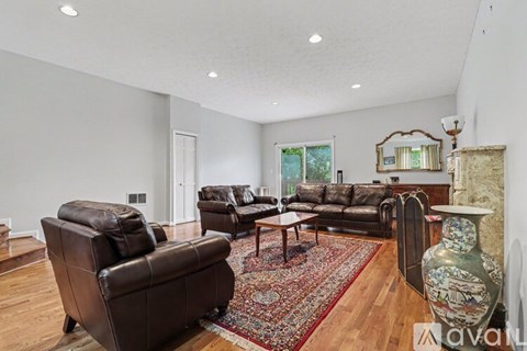 A living room with a brown leather couch and a rug.