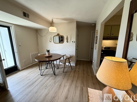 A living room with a round table and chairs, a lamp, and a mirror on the wall.