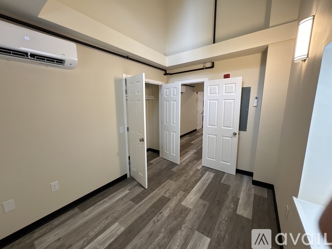 A hallway with a row of white doors and a wall-mounted air conditioner.