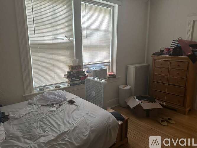 A messy bedroom with a bed, dresser, and window.