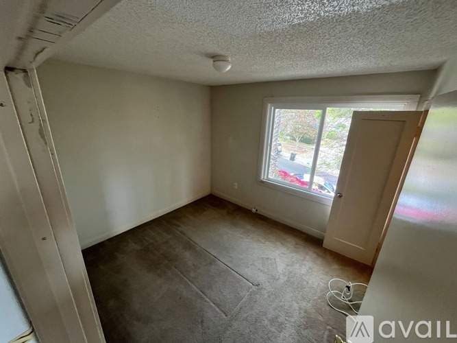 A room with a window and a door is available for rent.