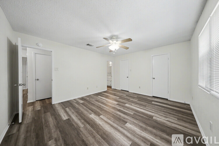 A spacious room with wood flooring and a ceiling fan.