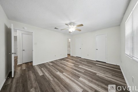 A spacious room with wood flooring and a ceiling fan.