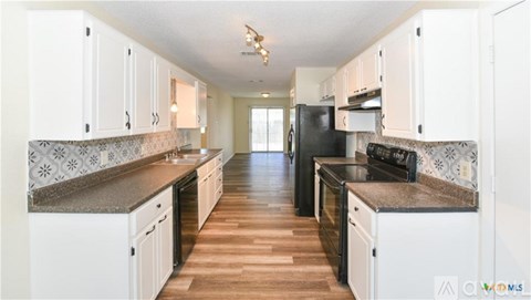 A kitchen with white cabinets and black appliances.