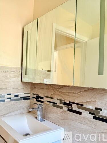 A white sink under a mirror with a black and white tile border.