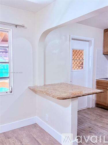 A room with a window, a door, and a countertop.