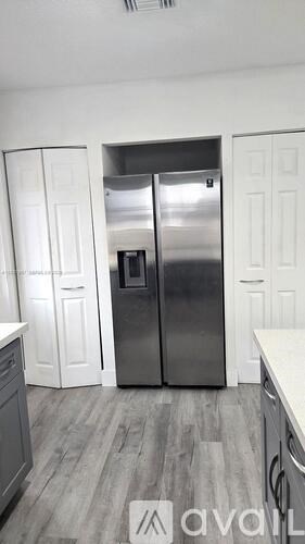 A kitchen with a stainless steel refrigerator and white cabinets.