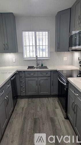 A kitchen with grey cabinets and a window.