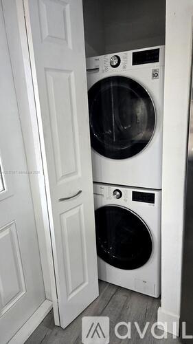 A white washing machine is in a small space between a door and a wall.