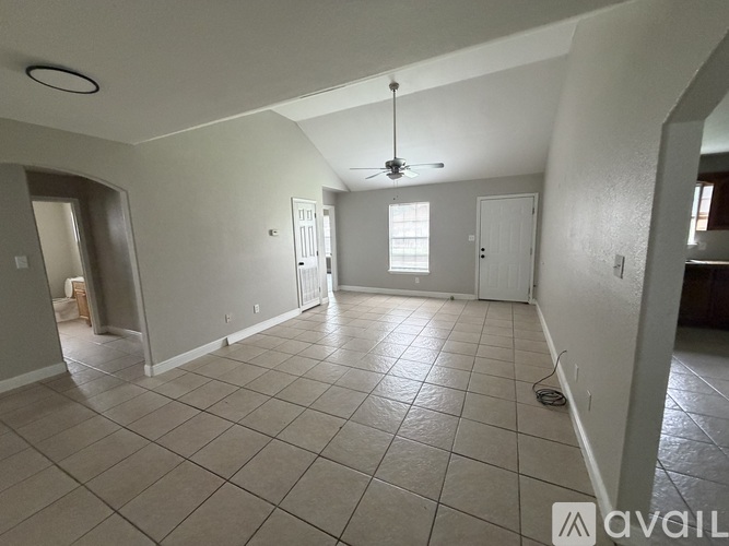 A spacious room with a ceiling fan and tiled flooring.