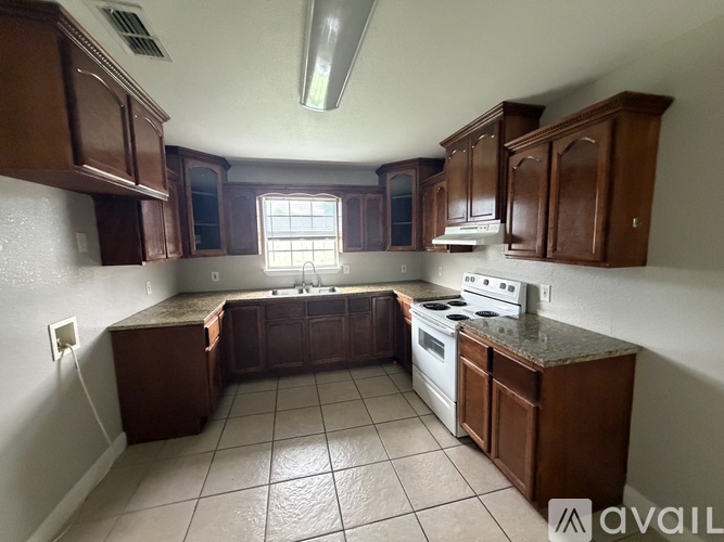 A kitchen with brown cabinets and a white stove top oven.
