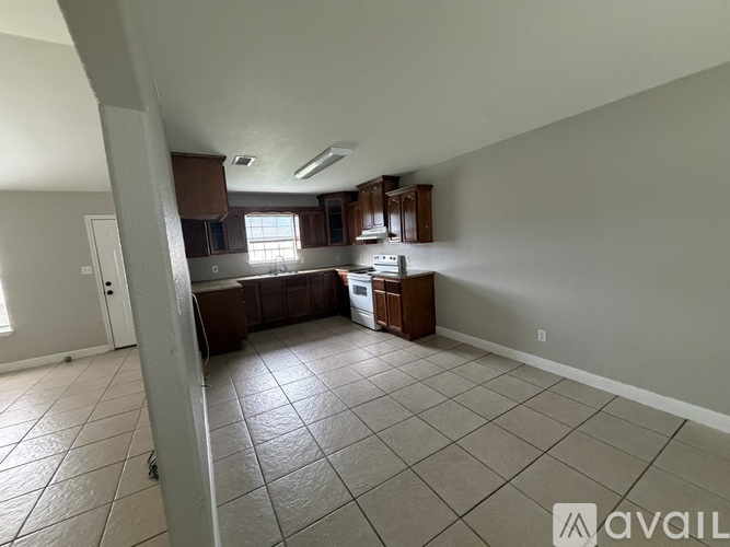 A spacious kitchen and living room with tile flooring and white walls.