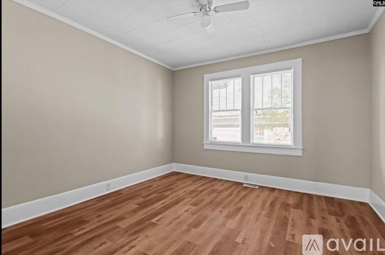 A room with a fan, wooden flooring and a window.