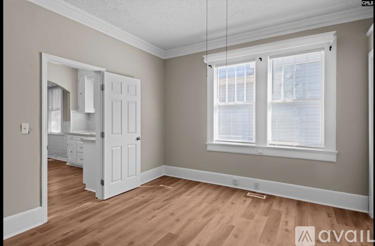 A room with a wooden floor and a window with blinds.
