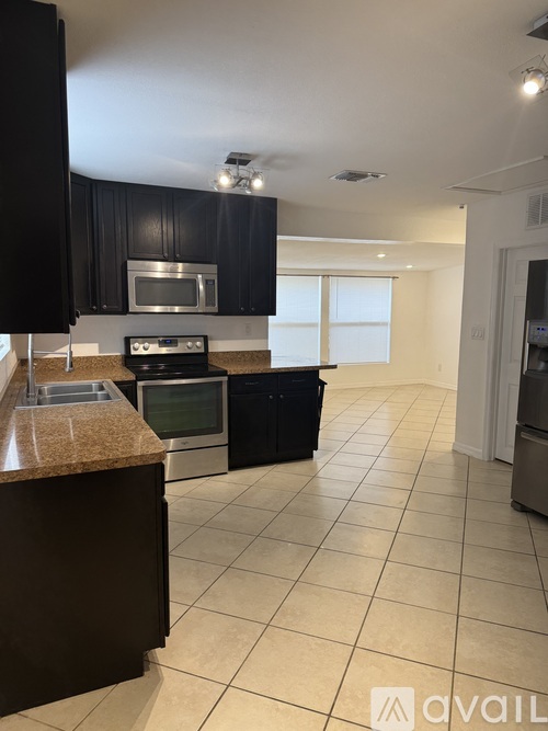 A kitchen with black cabinets and stainless steel appliances.